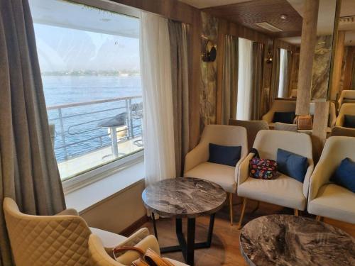 a room with chairs and a window with a view of the water at Nile Cruise 3 & 4 & 7 Nights in Luxor