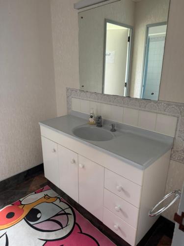a bathroom with a white sink and a mirror at Family house in happy farm in Pokeno
