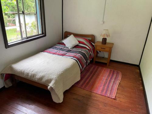 a small bed in a room with a table and a window at Cabaña de Campo in San José de la Mariquina