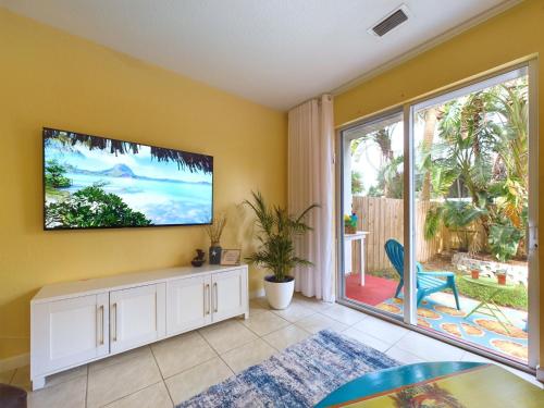a living room with a tv on a yellow wall at Coastal Bliss Retreat - Beach Vibes & Rockets in Cocoa Beach