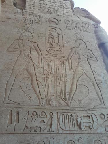 a relief on the side of a wall with hieroglyphics at Osiris Guest House in Abu Simbel