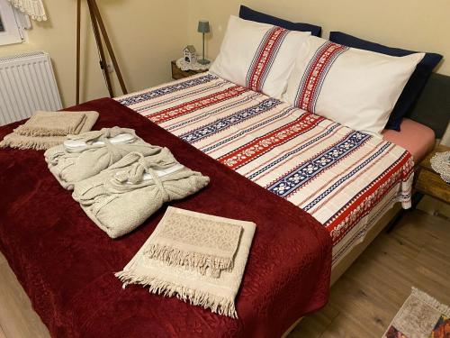 a bed with a red blanket and towels on it at Bukovički mir in Arandjelovac