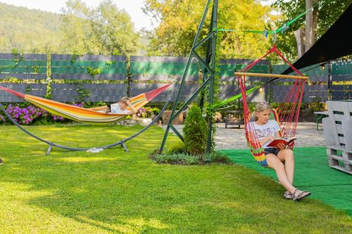 Dwie dziewczyny siedzą w hamakach na podwórku. w obiekcie Pod Gromadzyniem Resort w mieście Ustrzyki Dolne