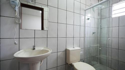 a bathroom with a sink and a toilet and a mirror at Residencial Adolfo - Mestre Naro in Bombinhas