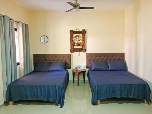 MezcalesにあるRancho Scarlettのベッドが2つあり、壁に時計がある寝室