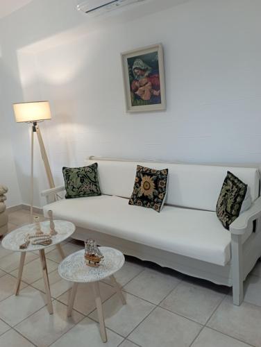 a living room with a white couch and two tables at Pano Chorio Tilos in Megálon Choríon