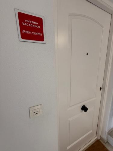 a white door with a sign on the wall at Apartamento con terraza en Mogro Playa de Usil in Mogro
