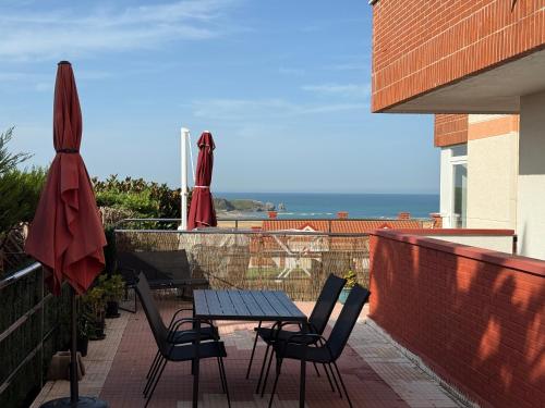 a table and chairs on a balcony with the ocean at Apartamento con terraza en Mogro Playa de Usil in Mogro