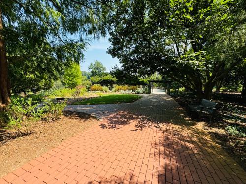 a brick path in a park with a bench and trees at Excelsior at the Manor House in Clemmons