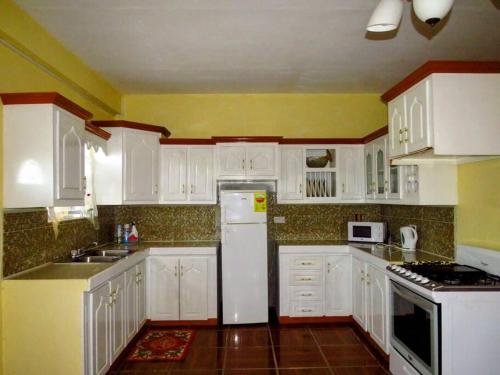 Herelle's Eden في Laborie: مطبخ بخزائن بيضاء وثلاجة بيضاء