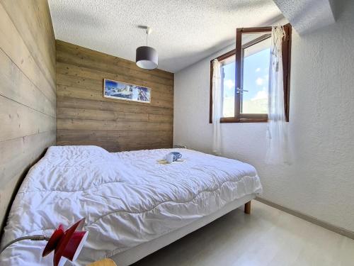 une chambre avec un lit blanc avec une fenêtre dans l'établissement Résidence Eperviere - Appartement spacieux · Au pied des pistes · Balcon MAE-1524, à Saint-Martin-de-Belleville
