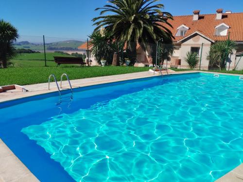 a large blue swimming pool in front of a house at Apartamento con terraza en Mogro Playa de Usil in Mogro