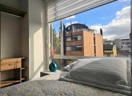 une chambre avec un lit et une grande fenêtre dans l'établissement MN 501 Espectacular Apartamento Vista La Macarena Bogotá, à Bogotá