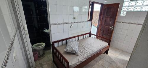 a small bathroom with a bed and a toilet at Casa, Piscina, Sinuca Churrasqueira, Ping Pong, Praia Guarujá in Guarujá