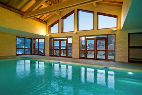 a large indoor swimming pool with glass windows at Charmant T2 au cœur du village in Hauteluce