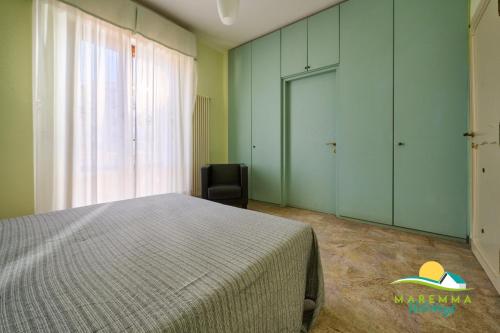 a bedroom with a bed and a chair and a window at Maremma Holidays Zot's Penthouse in Follonica