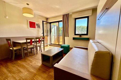 Cette chambre comprend un canapé, une table et des chaises. dans l'établissement Modern apartment with swimming pool in Mandelieu, à Mandelieu-la-Napoule