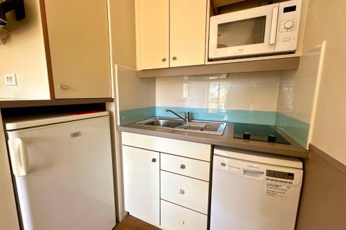 une petite cuisine avec un évier et un micro-ondes dans l'établissement Modern apartment with swimming pool in Mandelieu, à Mandelieu-la-Napoule