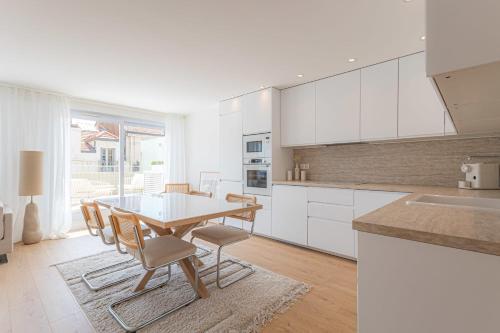 une cuisine avec des armoires blanches et une table et des chaises dans l'établissement Sublime 3 pièces entièrement rénové dans le centre de Cannes, à Cannes