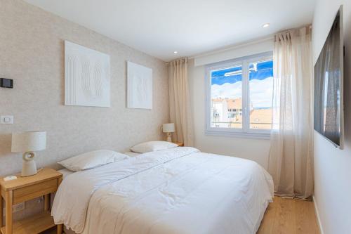 une chambre avec un lit blanc et une fenêtre dans l'établissement Sublime 3 pièces entièrement rénové dans le centre de Cannes, à Cannes