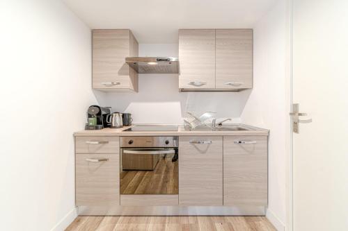 une cuisine avec des armoires blanches et un évier dans l'établissement Maison Fontanières Studio Navarre 1 person, à La Mulatière