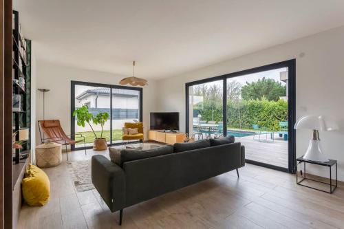 un salon avec un canapé et une télévision dans l'établissement Villa Tassin Piscine 6 Voyageurs, à Tassin-la-Demi-Lune