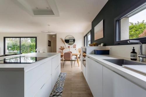 une cuisine avec comptoirs blancs et une salle à manger dans l'établissement Villa Tassin Piscine 6 Voyageurs, à Tassin-la-Demi-Lune