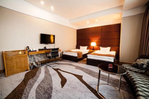 a hotel room with two beds and a desk at Absolute Hotel in Astana