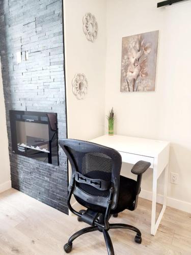 a desk and a chair in a room with a tv at Luxury Cozy Basement Suite in Leduc