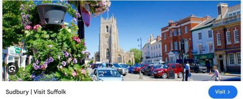 a town with a clock tower and a street with cars at Guest house paradiso in Great Cornard