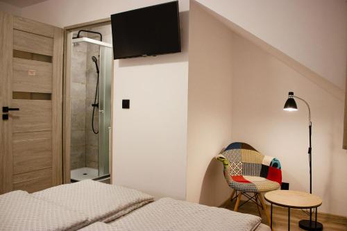 a bedroom with a bed and a chair and a table at Pod Gromadzyniem Resort in Ustrzyki Dolne