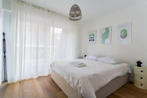 - une chambre blanche avec un grand lit et des rideaux blancs dans l'établissement Chic Bauhaus à Petite France Evasion et Design, à Strasbourg