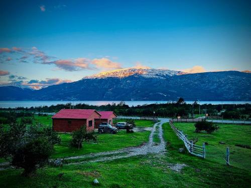a house in a field with a mountain in the background at Cabañas Piedra de Condores in Bahía Murta