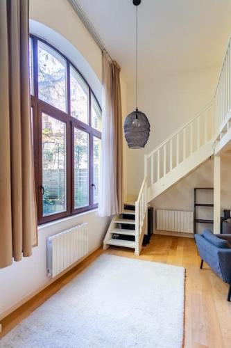 un salon avec un escalier et un canapé bleu dans l'établissement Duplex Spacieux au calme, à Strasbourg