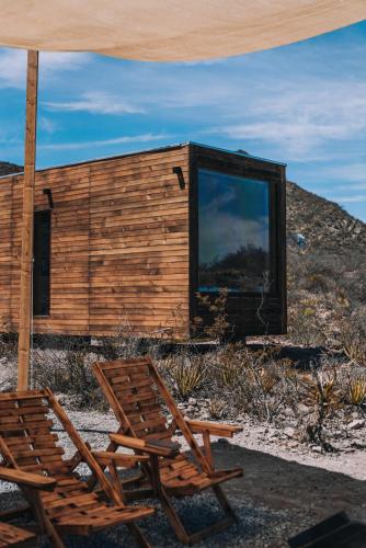 a couple of chairs and an umbrella and a building at Wander Cabins, Cabaña con Vista Única a la Sierra de Artega in Arteaga