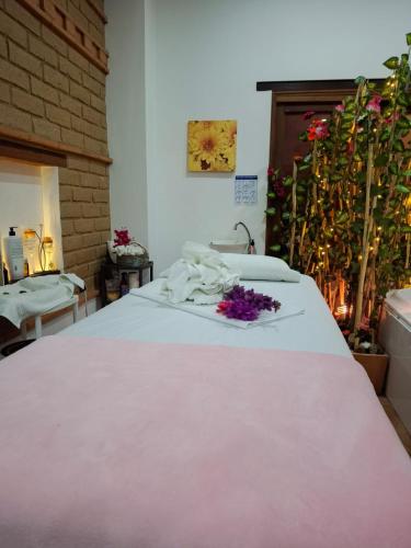 a bed with a white blanket and purple flowers on it at Hotel Villa Teresita in Sáchica