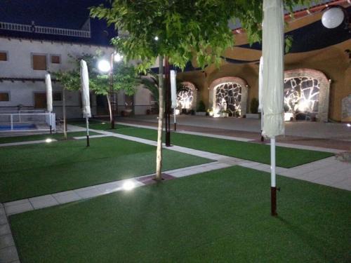 a courtyard with green grass and a building with lights at Hotel La Moraleda - Complejo Las Delicias in Villanueva del Arzobispo
