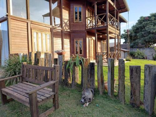 a dog laying in the grass in front of a wooden house at Casa de Campo Lazer Conforto e Wi Fi in Campo Limpo Paulista