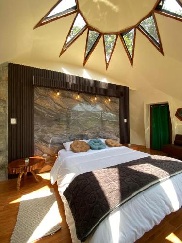 a bedroom with a large bed with a large window at GLAMPING MINDO SUYANA in Mindo