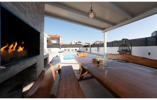 un patio con chimenea y mesa de madera en 3 Bedroom Cozy Home In Biograd Na Moru, en Biograd na Moru