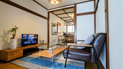 a living room with a leather chair and a television at Animal Art Apartment Type 22 in Ogikubo