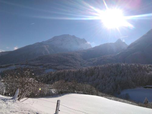 a view of a snow covered mountain with the sun at Hotel-Gasthof Nutzkaser in Ramsau