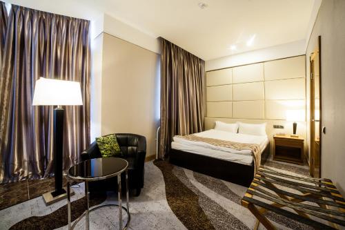 a hotel room with a bed and a chair at Absolute Hotel in Astana