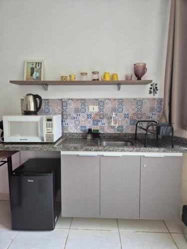 a kitchen with a sink and a microwave at Estúdio Charmoso no Centro de Apiaí in Apiaí