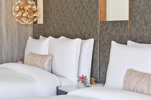 a hotel room with white beds and a chandelier at The St. Regis Longboat Key Resort in Longboat Key
