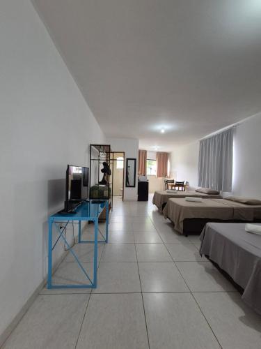 a room with three beds and a blue table in it at Estúdio Charmoso no Centro de Apiaí in Apiaí