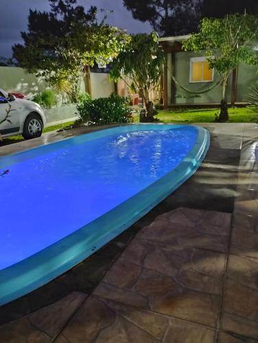a blue swimming pool in front of a house at Casa de praia natureza in Torres