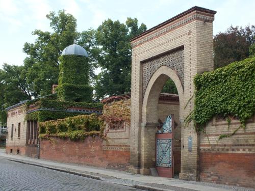 a brick wall with an arch and a tank on it at Bed&Breakfast Wagner "im Alten Pfarrhaus" in Neuruppin