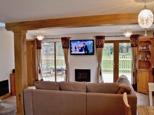 a living room with a couch and a tv on a wall at Dove Cottage in Ampney Crucis