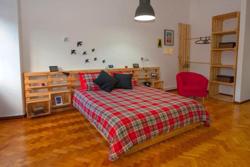 a bedroom with a bed with a plaid blanket and a red chair at Porto Downtown Flats in Porto